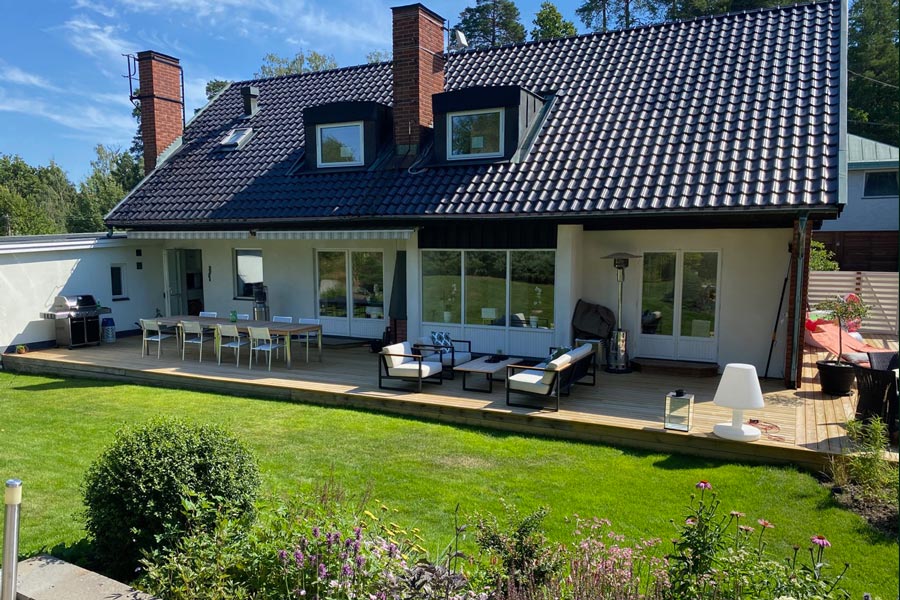 Villa med fin och grön trädgård och nybyggd altan en solig sommardag